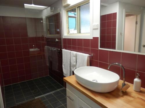 a red tiled bathroom with a sink and a shower at Wondai Hideaway Apartment in Wondai