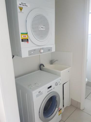 a washer and dryer in a small room at Direct Collective - Breeze on Brightwater in Mooloolaba