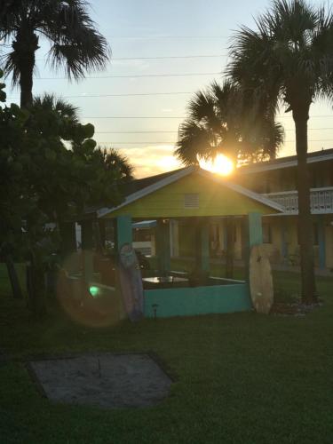a house with the sun setting behind a palm tree at South Beach Inn - Cocoa Beach in Cocoa Beach