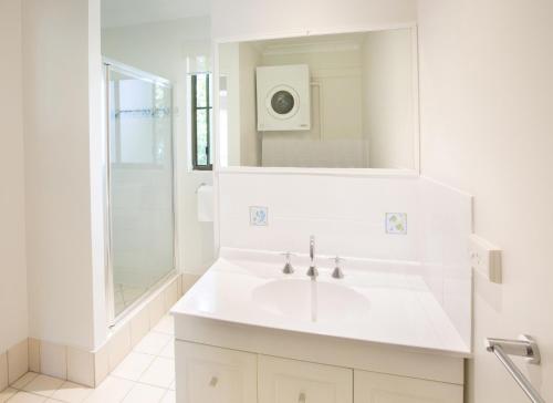 a white bathroom with a sink and a shower at Melaleuca Resort in Palm Cove