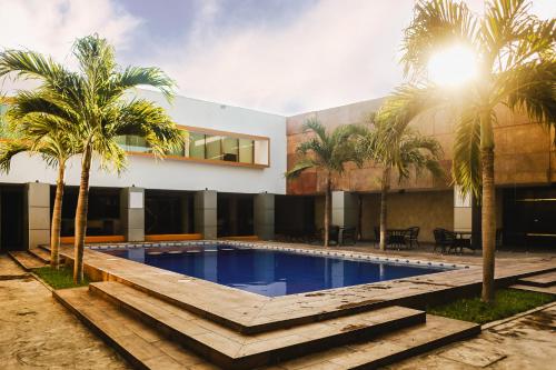 uma piscina com palmeiras em frente a um edifício em Hotel Plaza Mirador em Mérida