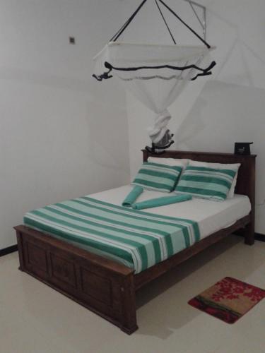 a bed with green and white striped sheets in a room at Sunset Surfing Beach Resort in Matara
