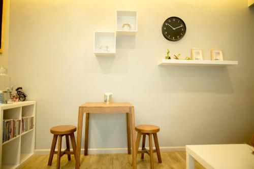 a kitchen with a table, chairs, and a clock on the wall at The Suvarnabhumi Apartment in Bang Kew Yai