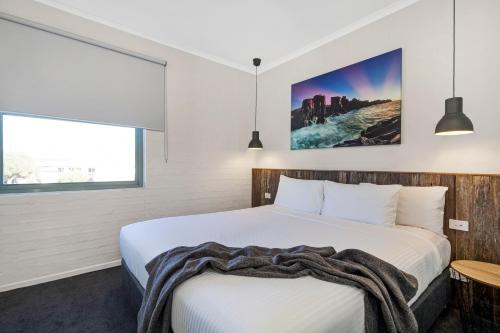 a hotel room with a bed, desk and a painting on the wall at Moonlight Bay Apartments in Rye