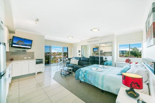 a bedroom with a bed and a living room at Suttons Beach Apartments in Redcliffe