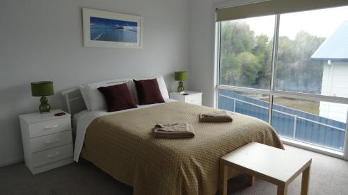 a white bedroom with a bed and a large window at Kangaroo Island Bayview Villas in Kingscote