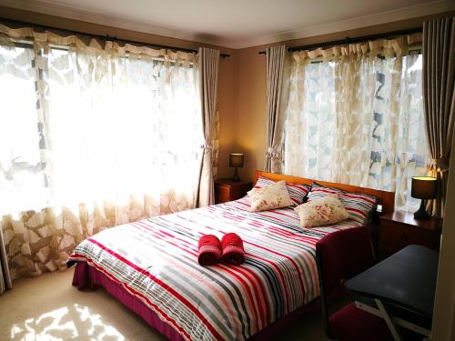 a bedroom with a bed with red slippers on it at Monique's Rose Room Prvt BthRm AC TV in Auckland
