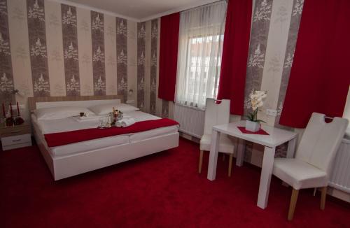 Hotel Restaurant Stöckl في Deutsch Altenburg: غرفة نوم بسرير وطاولة وكرسي