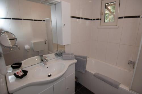 a white bathroom with a sink and a bath tub at Hotel Restaurant Stöckl in Deutsch Altenburg
