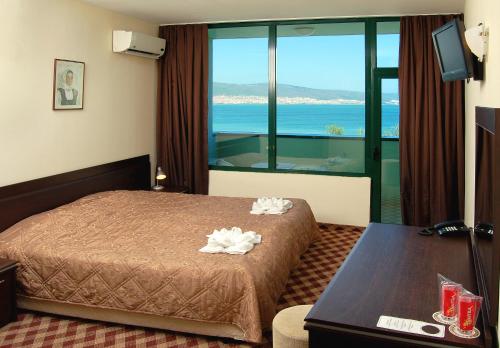 a hotel room with a bed and a large window at Hotel Caesars Palace in Sunny Beach