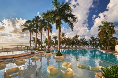 a swimming pool with chairs and palm trees at Mövenpick Hotel Mactan Island Cebu in Mactan