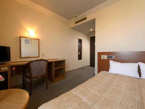 八戸市にあるホテルパールシティ八戸のベッドとデスクが備わるホテルルームです。