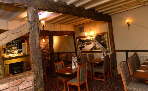 un restaurante con mesas y sillas y una chimenea en Vine, Stafford by The White Feather Group Ltd, en Stafford