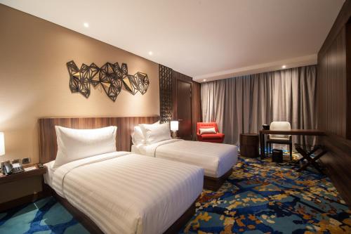 a hotel room with two beds and a desk at Grand Soll Marina Hotel in Tangerang