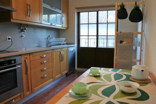 a kitchen with a table with cups and dishes on it at casa da ponte aljezur center in Aljezur