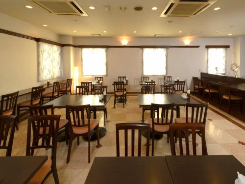 a dining room with tables and chairs and windows at Hotel Pearl City Hachinohe in Hachinohe