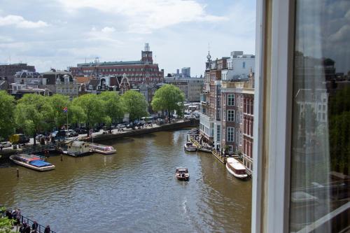 a view from a window of a river with boats at Hotel Nes Amsterdam in Amsterdam