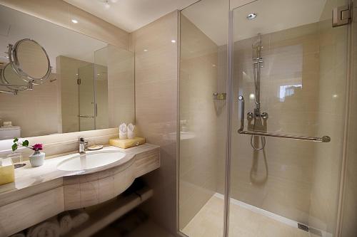 a bathroom with a glass shower and a sink at Grand Metropark Hotel Hangzhou in Hangzhou