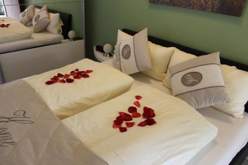 two beds with white sheets with red flowers on them at Ferienwohnung SONNENUHR in Bacharach