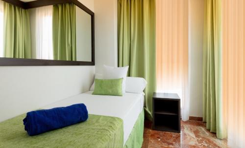 a bedroom with a bed and a mirror and green curtains at Magic Tropical Splash in Cala de Finestrat