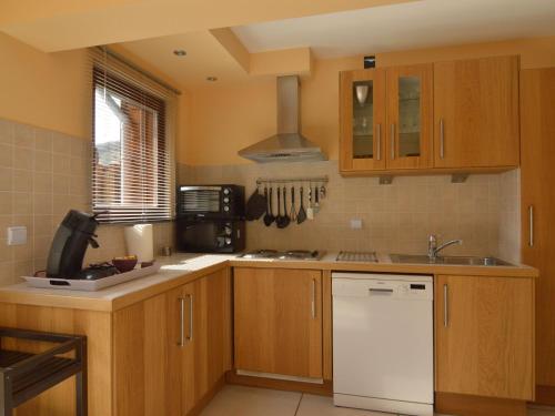 a kitchen with wooden cabinets and a white dishwasher at Cozy Cottage in Aywaille with Valley View in Aywaille