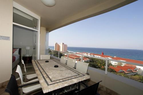 a balcony with a table and a view of the ocean at 503 Oyster Schelles in Durban
