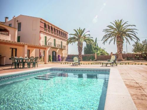 a swimming pool in front of a house with palm trees at Belvilla by OYO Can Bertu in Sant Pere Pescador
