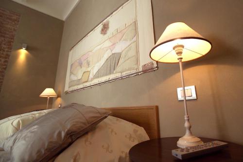 a lamp sitting on a table next to a bed at Rocche Costamagna Art Suites in La Morra