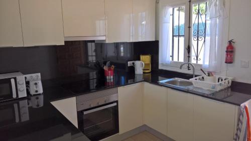 a kitchen with white cabinets and a black counter top at Vista Bahia II Apartments- top floor with balcony views & ground floor with garden and BBQ in Albir