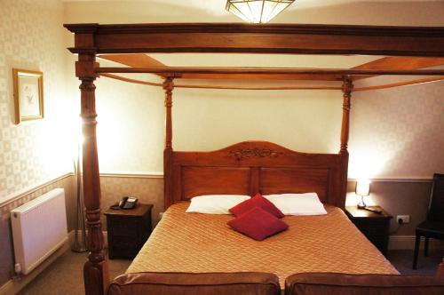 a bedroom with a canopy bed with two red pillows at York House Hotel in Wakefield