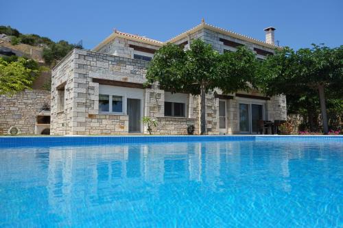 a large swimming pool in front of a house at Infinity Blue Villa in Koroni