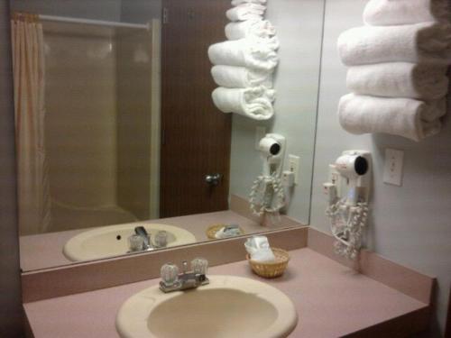 a bathroom with a sink and a mirror and towels at Quail's Nest Inn & Suites in Osage Beach