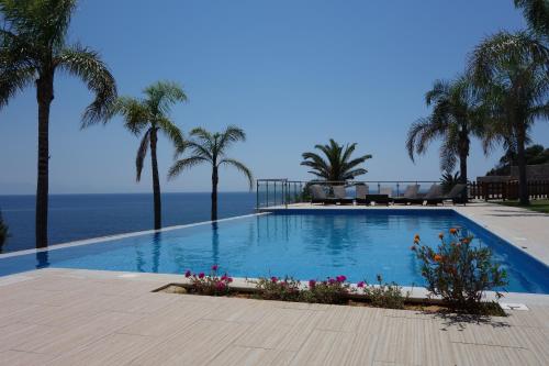 a swimming pool with palm trees and the ocean at Infinity Blue Villa in Koroni
