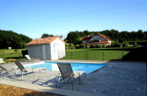 einen Pool mit zwei Stühlen und ein Haus in der Unterkunft Manoir Théas in Barraute-Camu