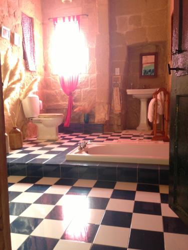 a bathroom with a tub and a checkered floor at Gozo Holiday Home -Tranquil and Serene in Għasri