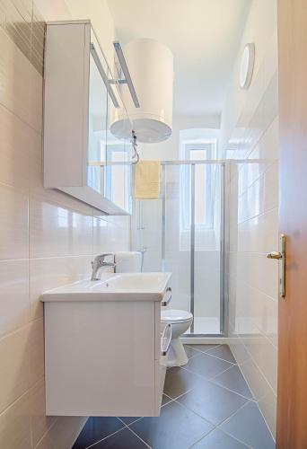 a white bathroom with a sink and a toilet at Apartment Zora & Natale in Pula