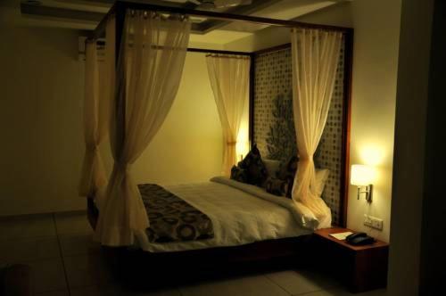 1 dormitorio con cama con dosel y cortinas blancas en Hotel Kalyan's - Mansingh Inn, en Khambhāliya