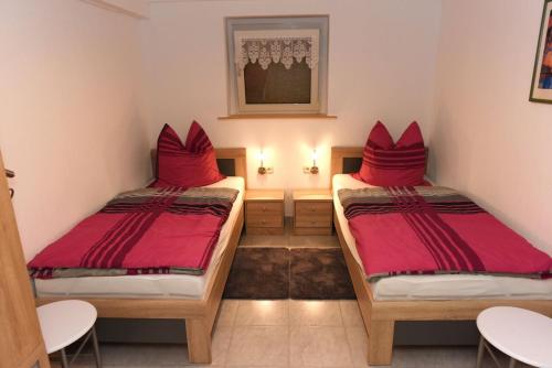 2 bedden in een kamer met rode kussens bij Beim Schneider in Ormont