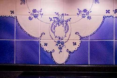 Apartments Madeira City Center في فونشال: جدار من البلاط الأزرق والأبيض مع مزهرية عليه