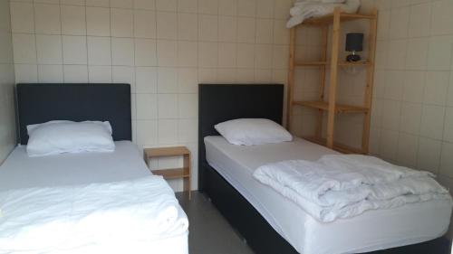 Dos camas en una habitación con mantas blancas. en De Zandhoorn, en De Panne