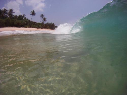 a large wave in the ocean on a beach at Haus am Meer "Wilde Ananas" in Koggala