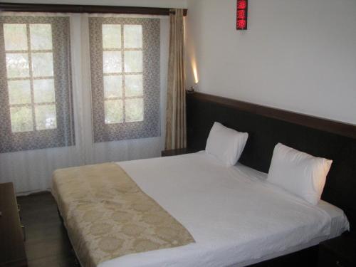 a bedroom with a white bed with two windows at Simre Hotel in Amasya