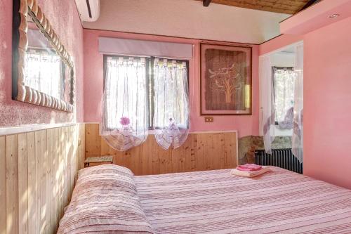 a bedroom with a bed with pink walls and windows at Secret Haven in La Croce