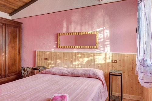 a bedroom with a bed and a pink wall at Secret Haven in La Croce