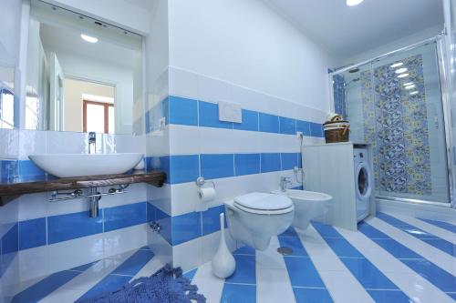een blauwe en witte badkamer met een wastafel en een toilet bij Mavi Apartments in Piano di Sorrento