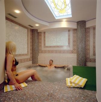 a man and a woman sitting in a bath tub at Hotel Patrizia Dolomites Glamour in Moena