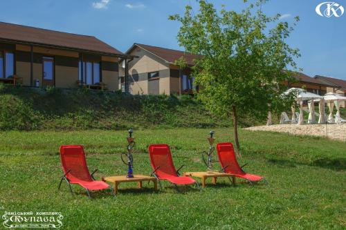 four red chairs and a table in the grass at Hotel Complex Kupava in Podvorki
