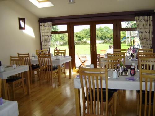 un comedor con mesas y sillas blancas y ventanas en Alverna House B&B, en Athlone