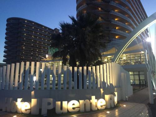 a sign in front of a building with a palm tree at Hotel Puente Real in Torremolinos