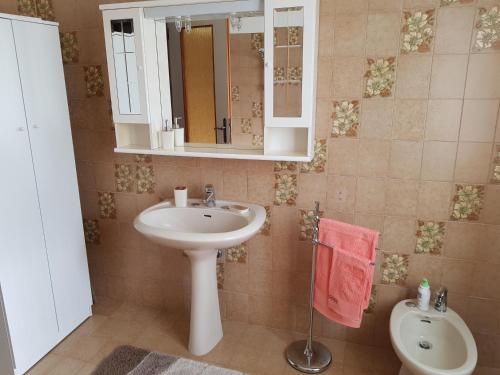 bagno con lavandino, specchio e servizi igienici di Appartamento Nerio a Múggia